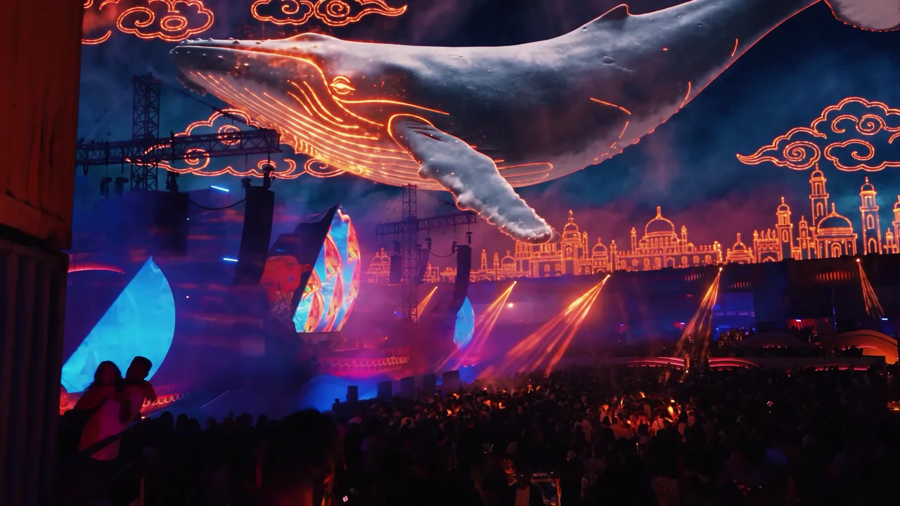 The giant whale breaking into glowing embers above the audience